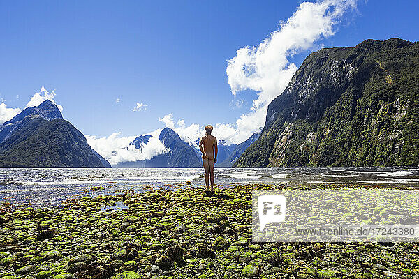Neuseeland  Südinsel  Rückansicht eines nackten Mannes mit Blick auf das fließende Wasser des Milford Sound