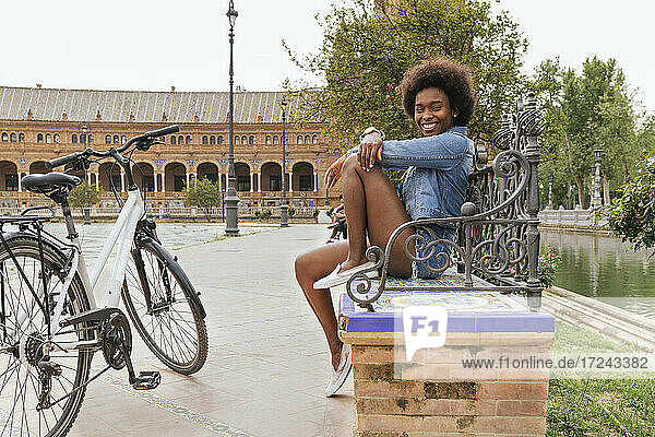 Glückliche Frau auf Bank sitzend mit Fahrrad