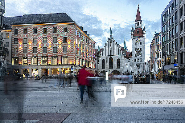 Incidental people walking on footpath during dusk at Marienplatz with Old Town Hall of Munich  Bavaria  Germany