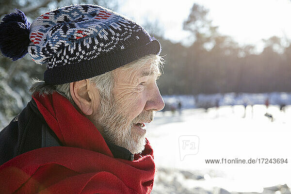 Älterer Mann mit rotem Schal und Strickmütze an einem sonnigen Tag im Winter