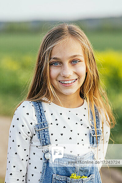 Lächelndes blondes Mädchen auf einem landwirtschaftlichen Feld