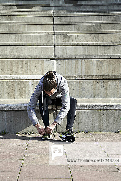 Mann bindet Schnürsenkel  während er auf einer Treppe sitzt