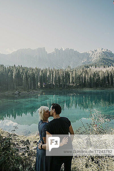 Ein Paar küsst sich am Carezza-See an einem sonnigen Tag in Südtirol  Italien