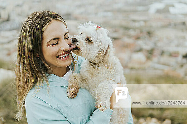 Cheerful woman smiling while holding maltese dog