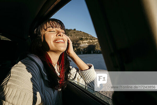 Glückliche Frau mit geschlossenen Augen reist im Auto