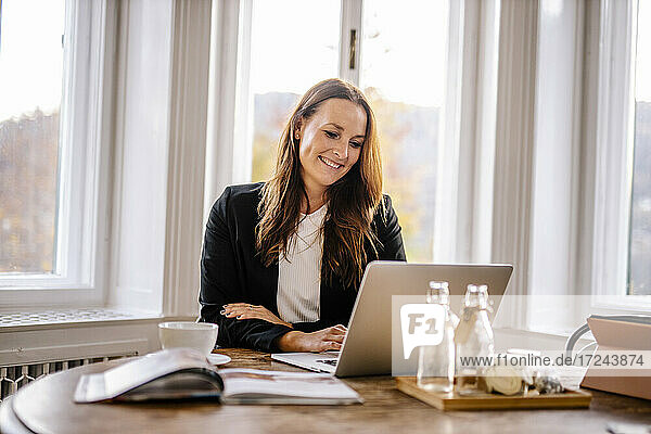 Businesswoman using laptop while sitting in office