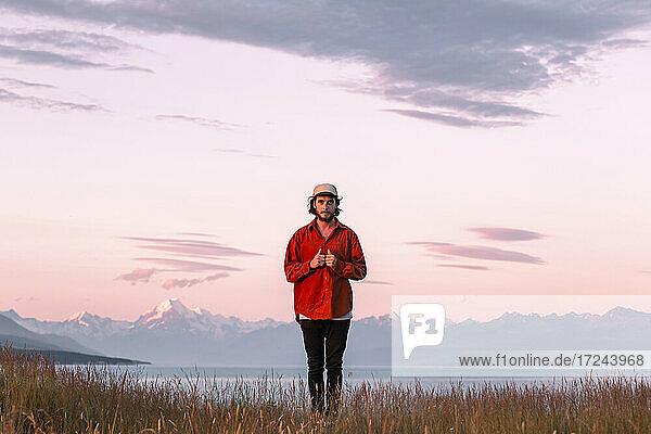 Neuseeland  Canterbury  Frontansicht eines jungen Mannes über dem Lake Pukaki bei Sonnenuntergang