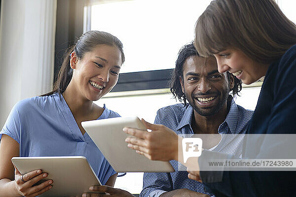 Businesswoman explaining male and female colleague over digital tablet at office