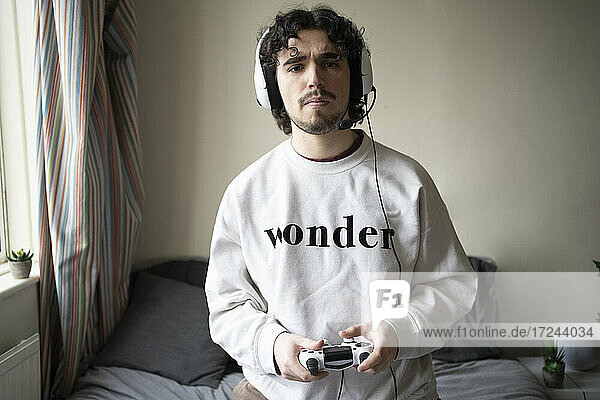 Man with headset holding game controller at home