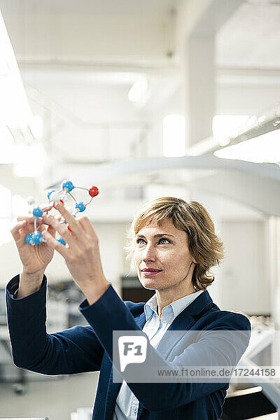 Mature professional looking at molecule model in printing factory