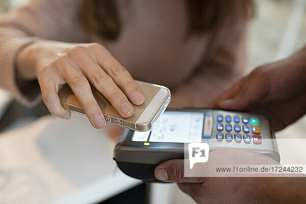 Frau bezahlt im Restaurant mit ihrem Smartphone
