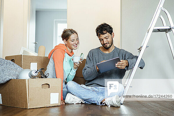 Junges Paar diskutiert über digitales Tablet in der neuen Wohnung