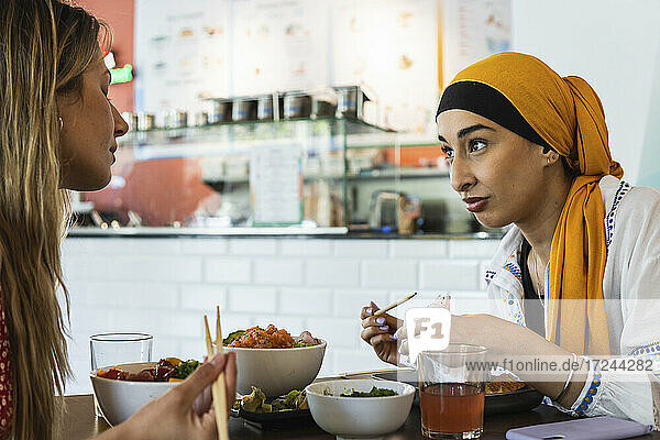 Young women talking with each other while having food in restaurant