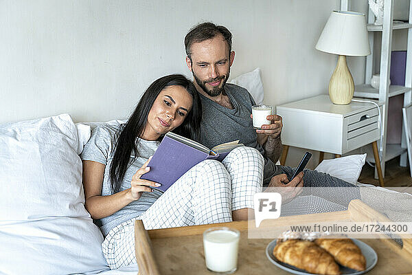 Mann und Frau frühstücken zu Hause auf dem Bett