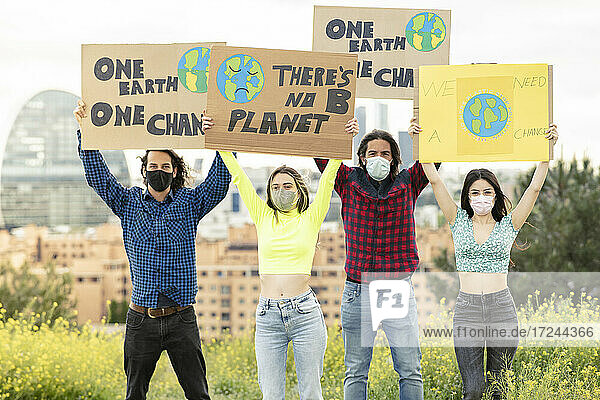 Männer mit Frauen  die ein Transparent inmitten von Pflanzen in der Stadt während der Pandemie halten