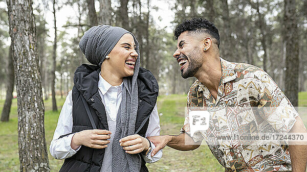 Young man laughing with woman in forest