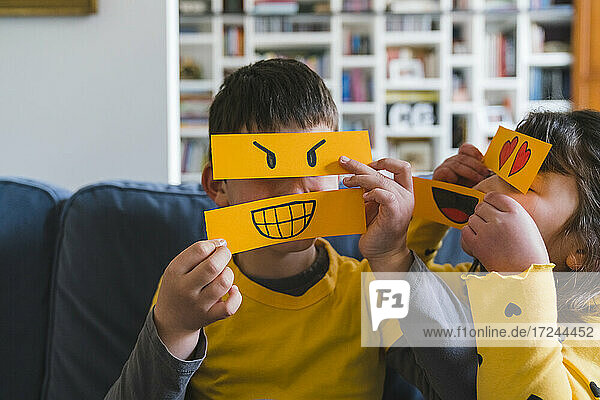 Mädchen und Junge spielen mit Emoticons zu Hause