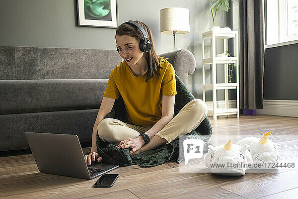 Frau mit Kopfhörern arbeitet zu Hause am Laptop