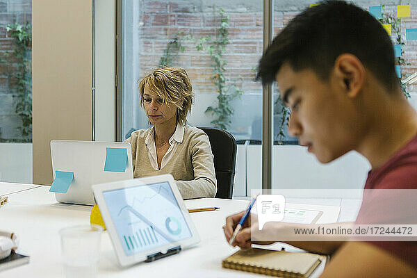Männliche und weibliche Unternehmer bei der Arbeit am heißen Schreibtisch im Büro