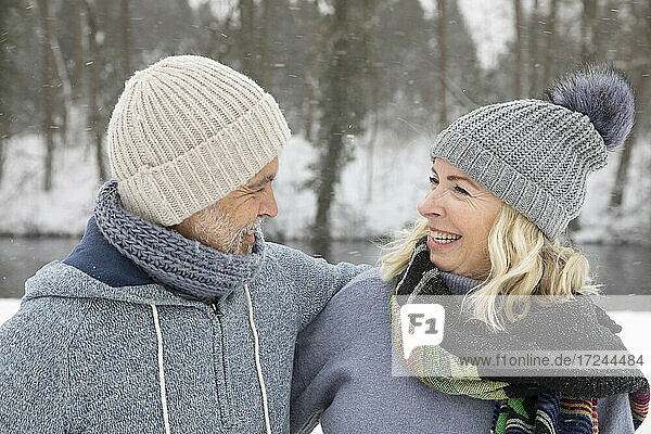 Happy senior couple in warm clothing looking at each other during winter