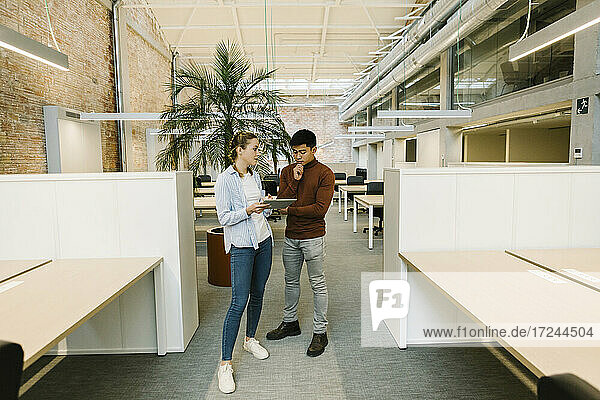 Männliche und weibliche Fachkräfte arbeiten mit einem digitalen Tablet im Coworking-Büro