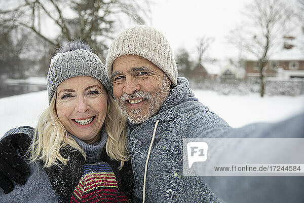 Mann umarmt Frau beim Selfie machen im Winter