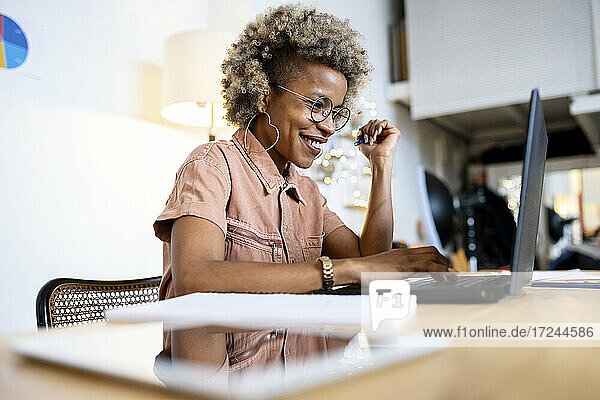 Lächelnde weibliche Fachkraft  die einen Laptop bei der Arbeit im Heimbüro benutzt