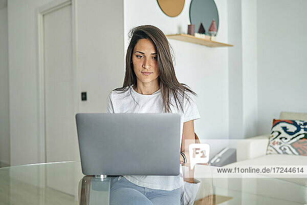 Mittlere erwachsene Frau benutzt Laptop zu Hause