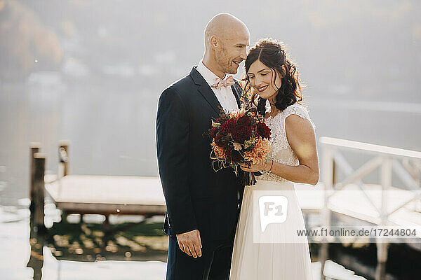 Paar im Hochzeitskleid umarmt sich am See