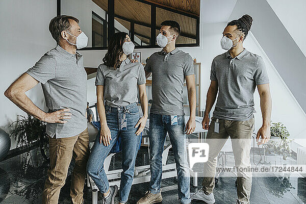Male and female physical therapists wearing protective face mask while discussing in practice