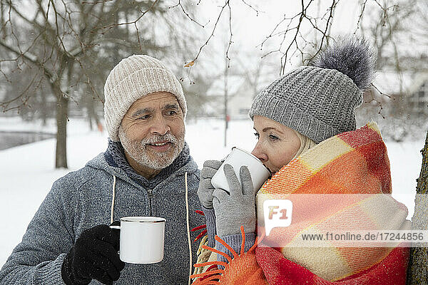 Man looking at woman drinking tea in mug during winter