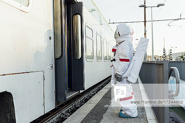 Junge Astronautin steht am Eingang eines Zuges am Bahnhof