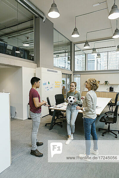 Male and female entrepreneurs playing soccer ball in coworking office