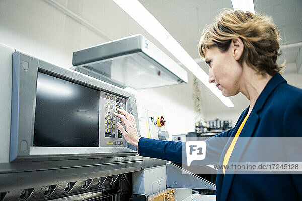 Weibliche Führungskraft bei der Kontrolle einer Maschine in einer Druckerei