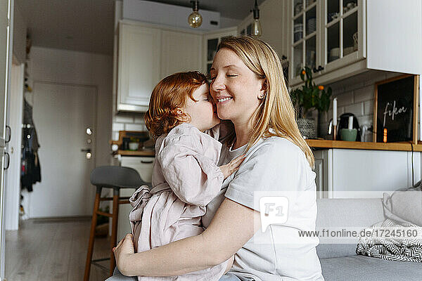Lächelnde schwangere Frau umarmt Tochter in der Küche zu Hause