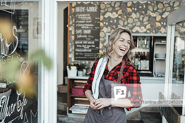 Cheerful businesswoman standing at cafe entrance