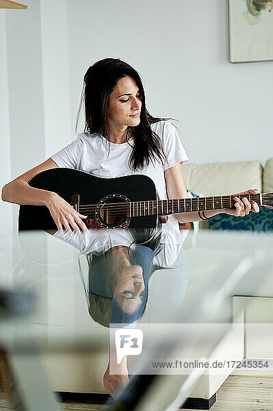 Mid adult Frau spielt Gitarre zu Hause