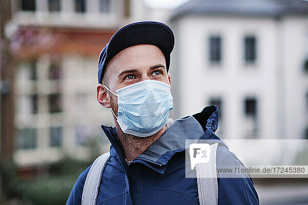 Mann mit grauen Augen  der wegschaut  während er während einer Pandemie eine Schutzmaske trägt