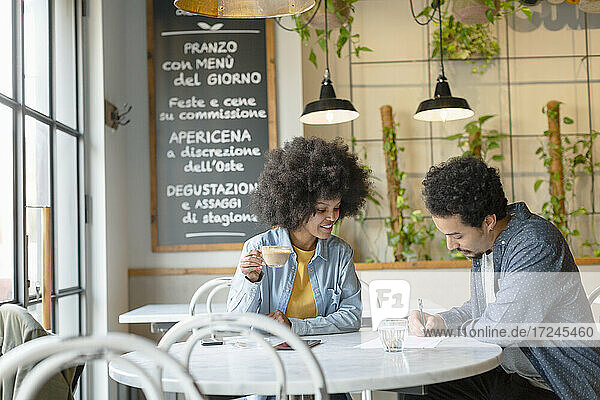Unternehmerin betrachtet männlichen Kunden bei der Vertragsunterzeichnung in einem Cafe