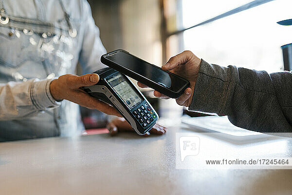 Kunde nutzt Smartphone für Online-Zahlung in einer Bar