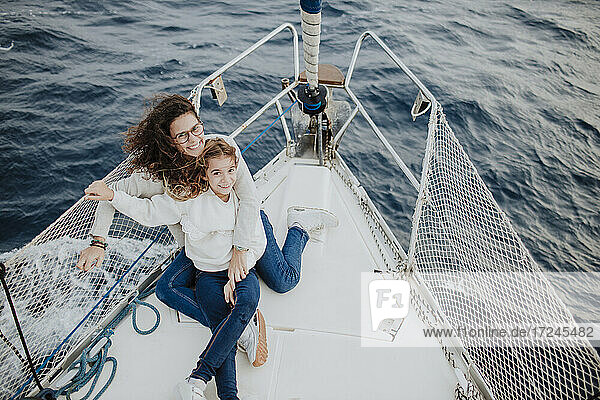 Smiling mother and daughter enjoying vacation on sailboat