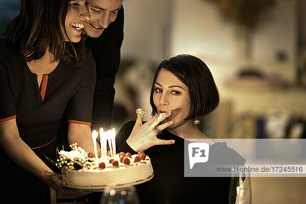 Schöne Frau isst Kuchen von männlichen und weiblichen Freunden während einer Feier zu Hause
