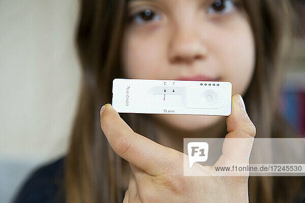 Girl holding rapid diagnostic test at home showing negative result