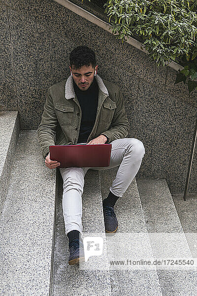 Businessman working on laptop while sitting on steps