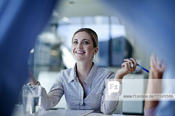 Young female professional smiling while discussing in meeting at office