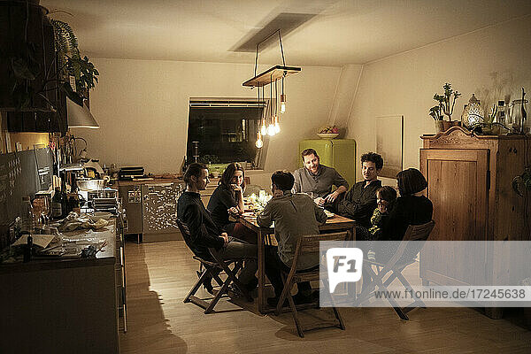 Male and female friends talking at dining table in kitchen