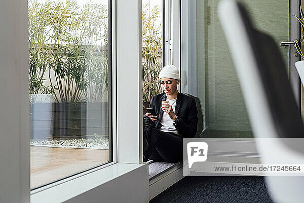 Entrepreneur using mobile phone while sitting on doorway