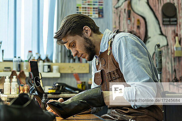 Männlicher Handwerker  der in einer Werkstatt einen Schuh repariert