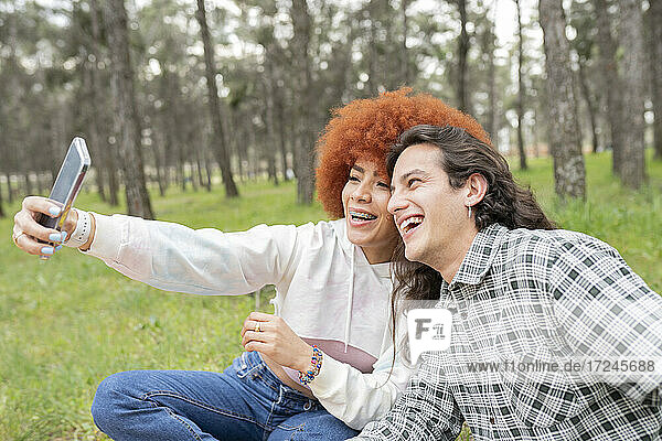 Glückliche junge Frau mit Mann nimmt Selfie durch Smartphone im Wald