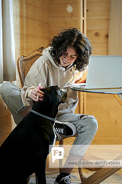 Lächelnde Frau streichelt Hund zu Hause